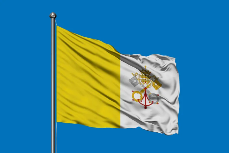 flag of vatican city waving in the wind against deep blue sky