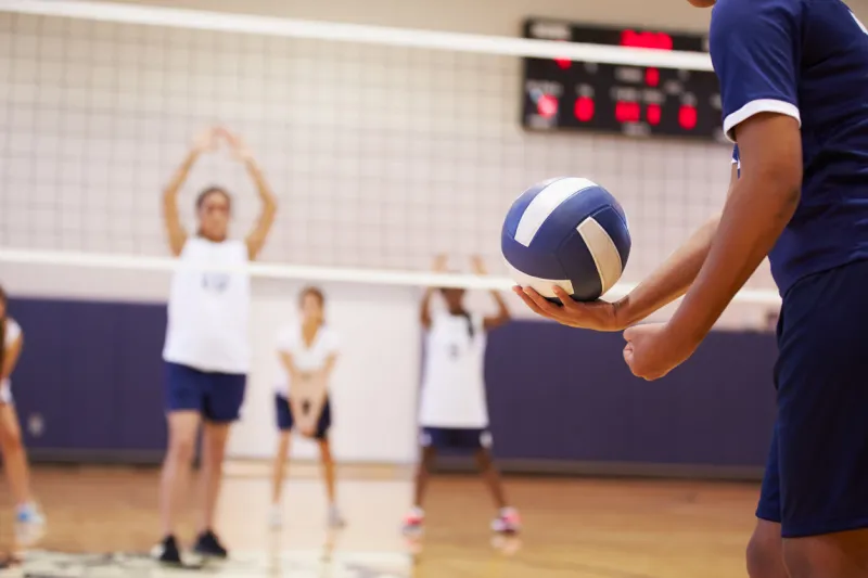 high school volleyball match in gymnasium with ball