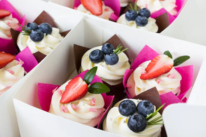 cupcakes decorated with strawberry and blueberries in delivery paper box sweet food delivery
