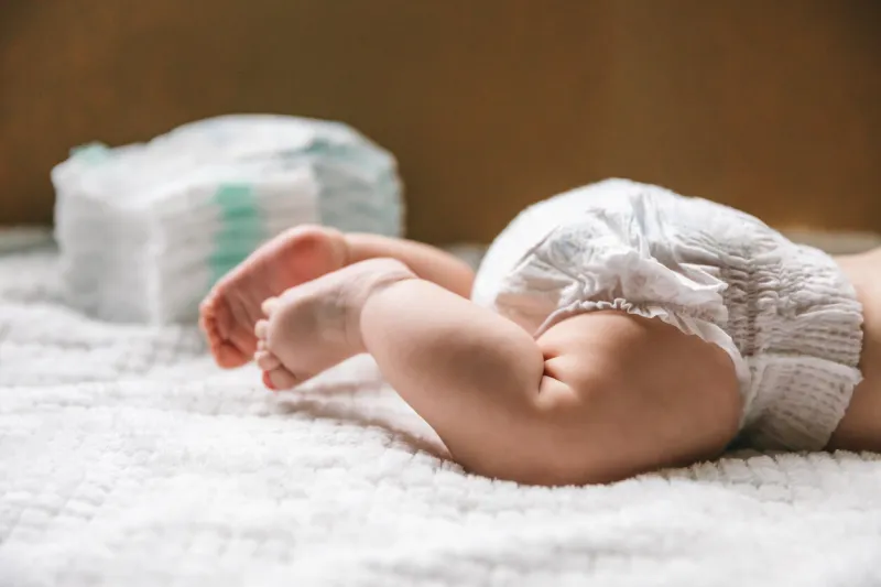 a baby in a diaper at the age of two months and a stack of diapers how to choose baby diapers