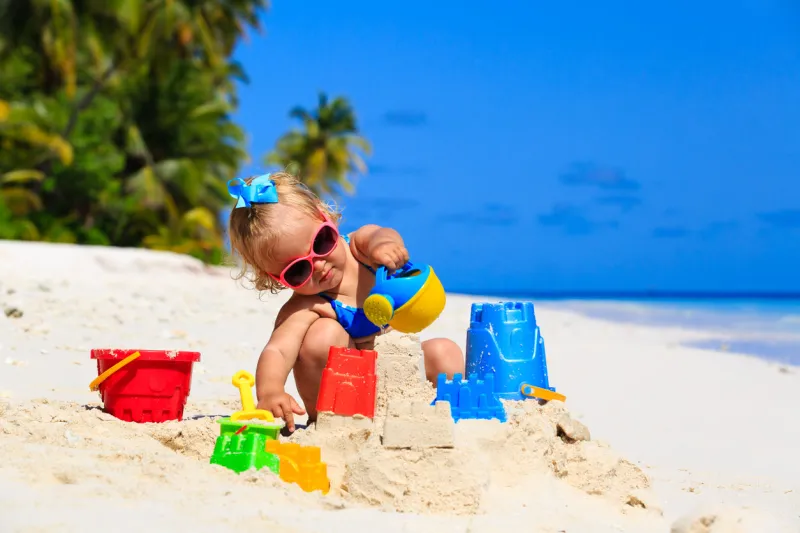 cute little girl playing with sand on tropical beach