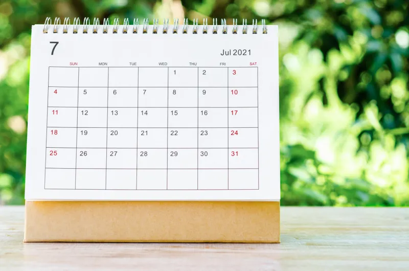 july 2021 calendar desk for organizer to plan and reminder on wooden table on nature background