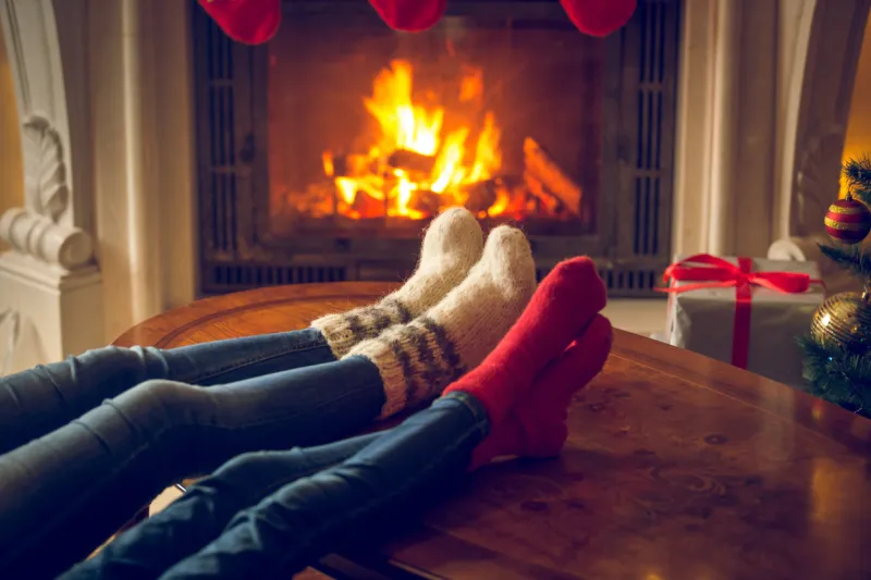 closeup toned image of female and and feet in wool socks warming at fireplace at chalet