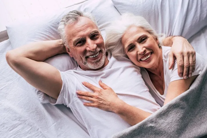 the happy elderly couple laying on the bed
