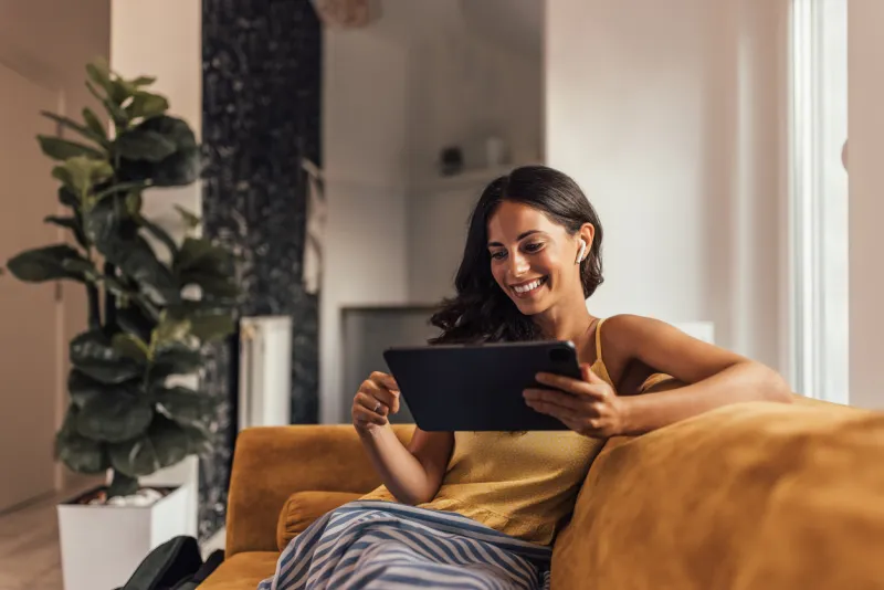 happy adult woman, reading a book on her tablet, while relaxing
