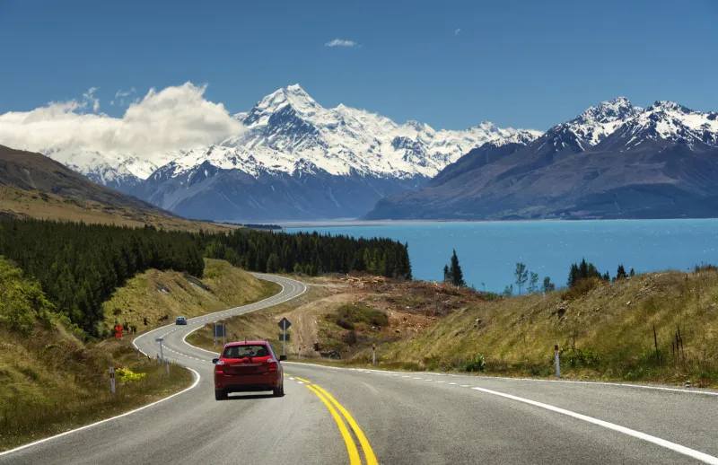 red car going to the beautiful landscape lake tekapo, mtcook, lupines fields, south island new zealand