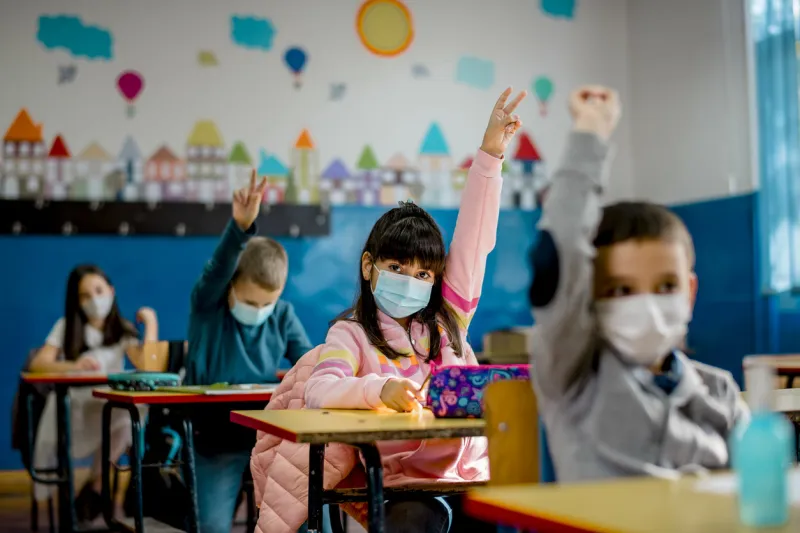 elementary schoolchildren wearing a protective face masks in the classroom education during epidemic