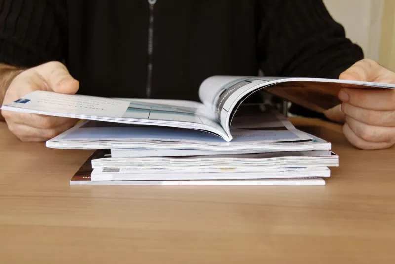 man sitting at the desk in office with magazine in hands