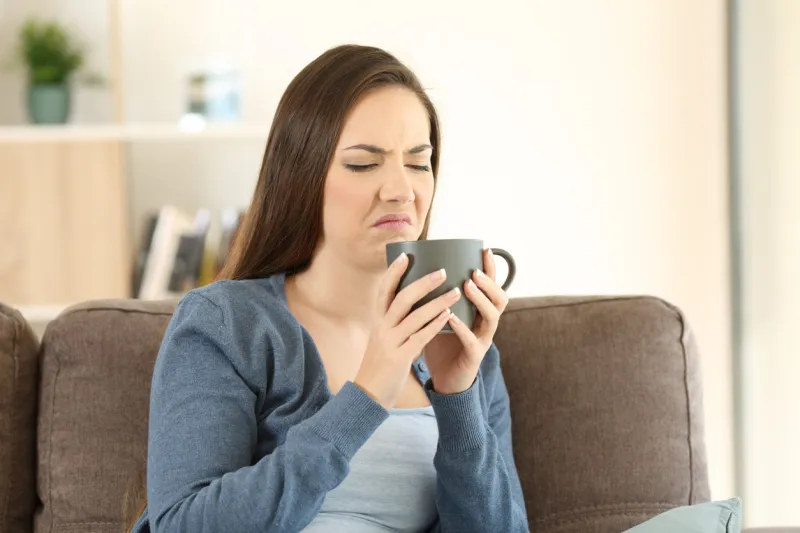 woman suffering drink bad taste sitting on a couch in the living room at home