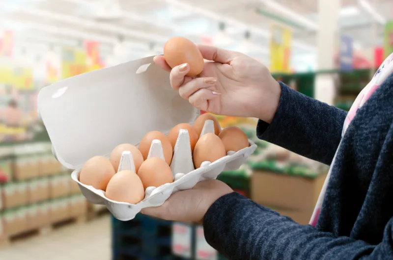 woman buys eggs in the supermarket egg store supermarket price expensive grocery shop concept