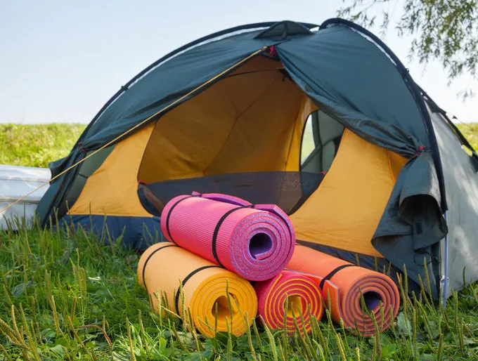 open tent and rolled sleeping pads campsite