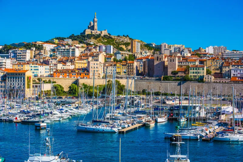 marseille in may the water area of the old port - yachts, speedboats and fishing boats on the hill - splendid basilica of notre-dame de la garde