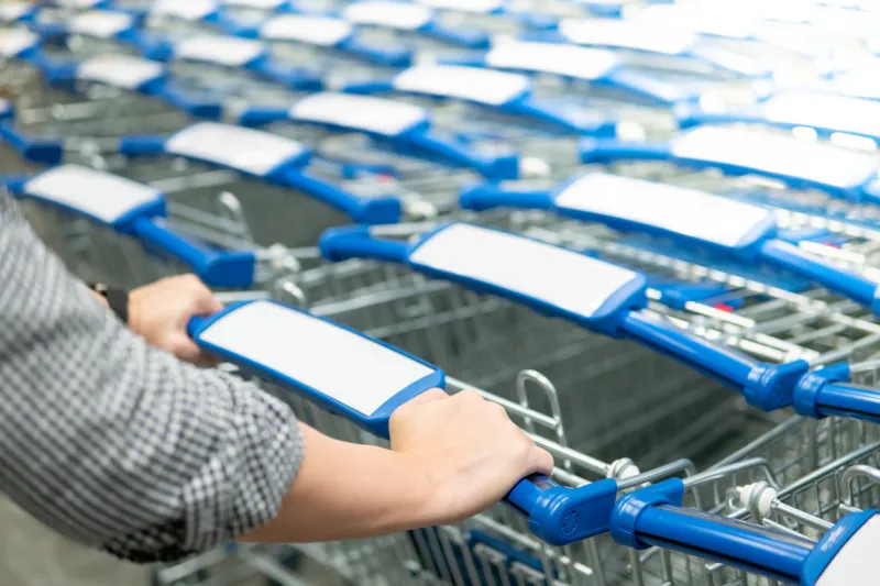 male hand shopper pulling shopping cart (trolley) from row in supermarket or grocery store shopping lifestyle concept