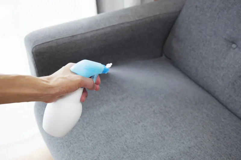 sprayed air freshener in hand on home interior background