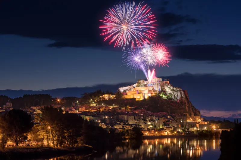 the city of sisteron with 14th of july fireworks (bastille day celebration) over the citadel at twilight durance valley, alpes-de-haute-provence, france