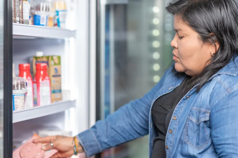 close up cropped photo of a latina lady buying cured meats in a supermarket