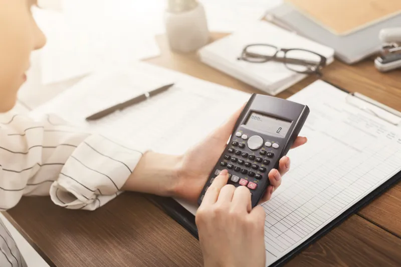 businesswoman calculating gains and losses using calculator at workplace , pushing button financial report concept, copy space