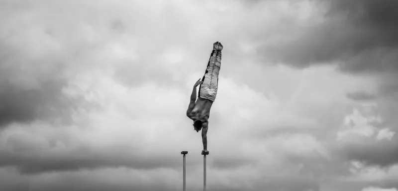 flexible male circus artist keep balance by one hand against amazing cloudscape individuality, outstanding and originality