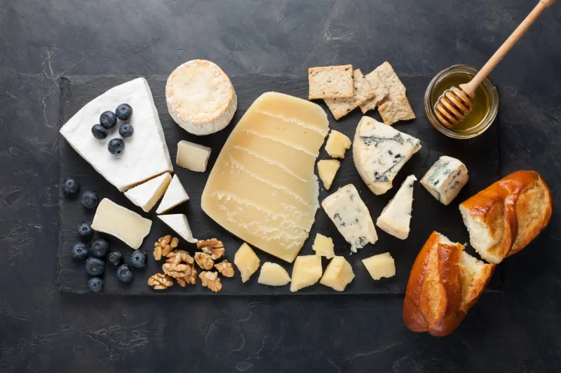 tasting cheese dish on a dark stone plate food for wine and romantic date, cheese delicatessen on a black concrete background top view