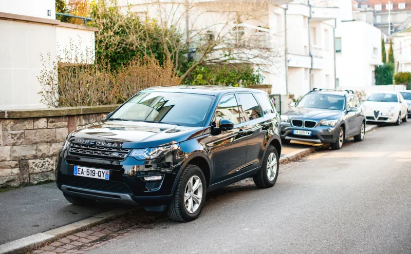 strasbourg, france - feb 13 2017  new luxury land rover discovery executive suv parked on a french street with multiple cars parked in background
