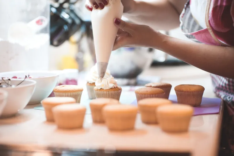 woman making creamy top of cupcakes closeup selective focus