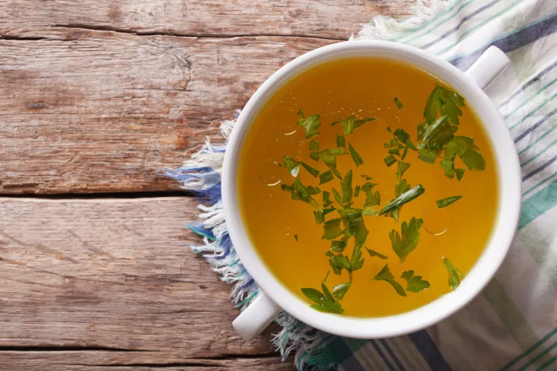 tasty meat broth with parsley in a white bowl closeup horizontal view from above