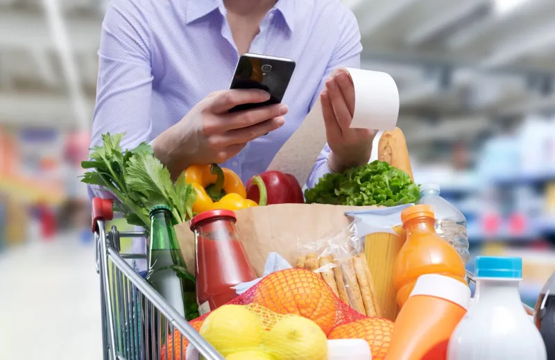 woman checking the grocery receipt using her smartphone