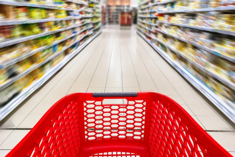 red empty shopping cart in a supermarket aisle, motion blur
