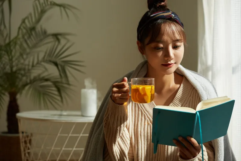 a young asian woman relaxing at home drinking fruit tea