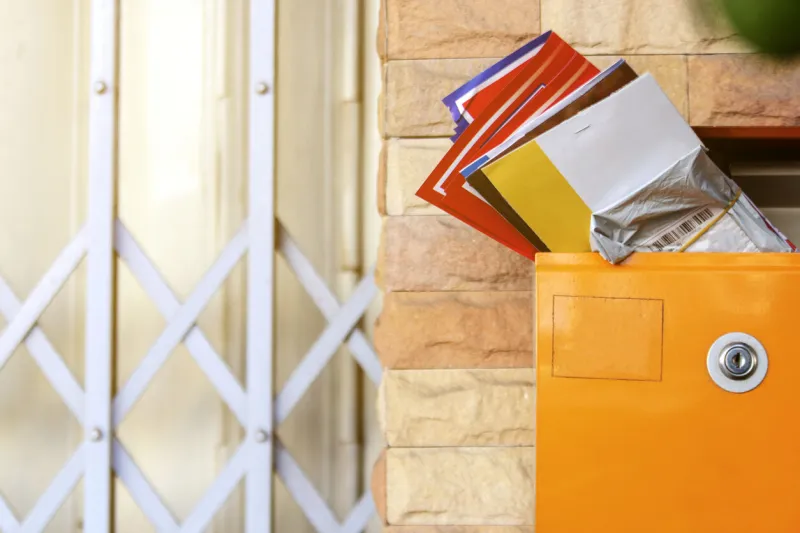 modern lockable yellow postbox with many mail letter inside brick wall and steel doors background