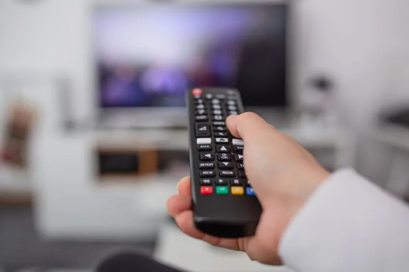 watching tv and using remote controller hand with remote controller changing channels or opening apps on smart tv