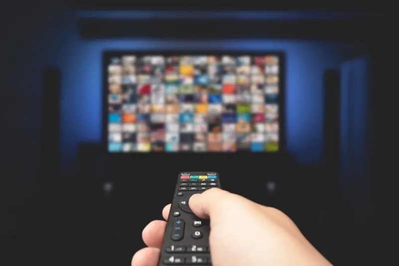 multimedia video concept on tv set in dark room man watching tv with remote control in hand