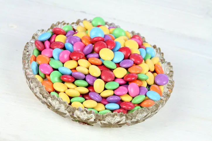 chocolate buttons in colors of rainbow delicious candies on white wooden table