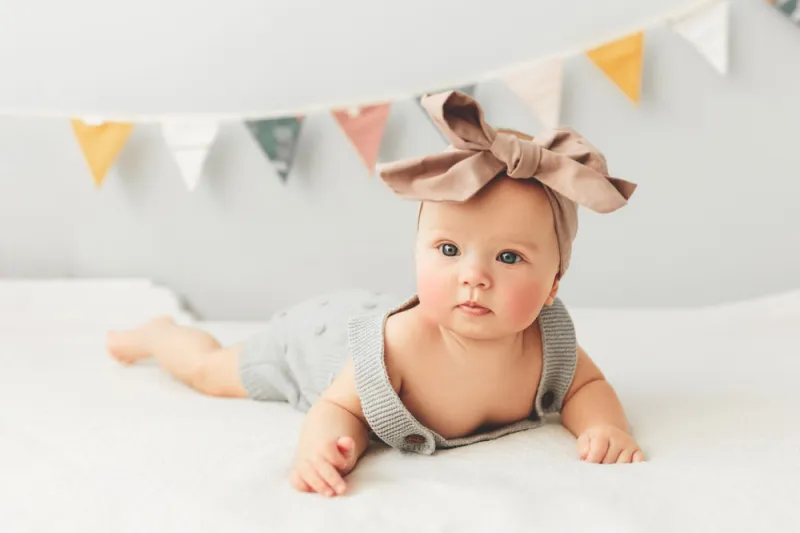 portrait of a cute 3 months baby lying down on a blanket, bow on the head