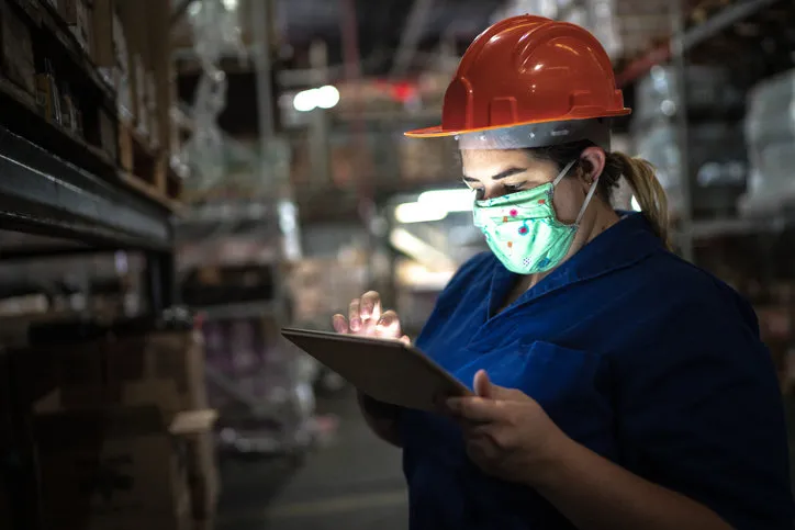 portrait of mid adult woman wearing face mask using digital tablet - working at warehouse   industry
