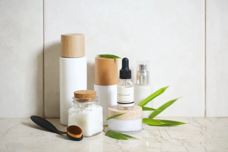 face cream, serum, lotion, moisturizer and sea salt among bamboo leaves in the bath