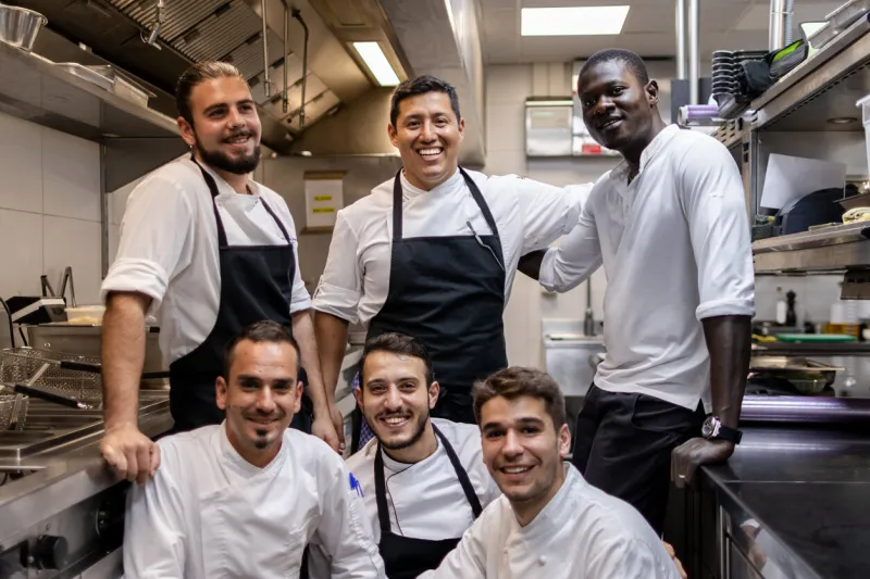 multi ethnic cooking team posing for a team photo in the kitchen at work