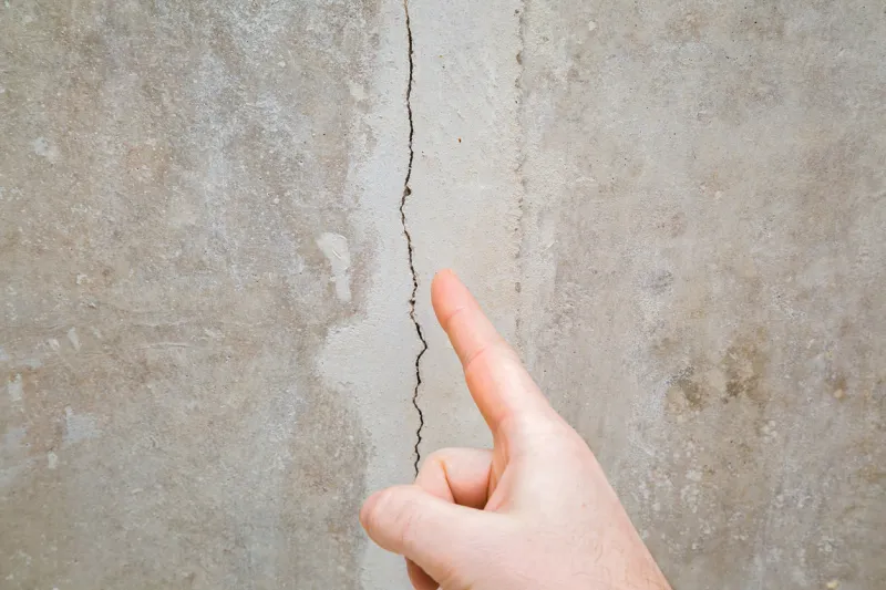 man hand finger pointing to cracked ceiling building problem and solution concept closeup