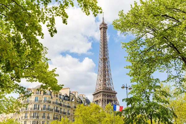 vue de paris avec la tour eiffel, un drapeau français, quelques arbres et un immeuble parisien typique des concepts de voyage et d'architecture sur la capitale de la france