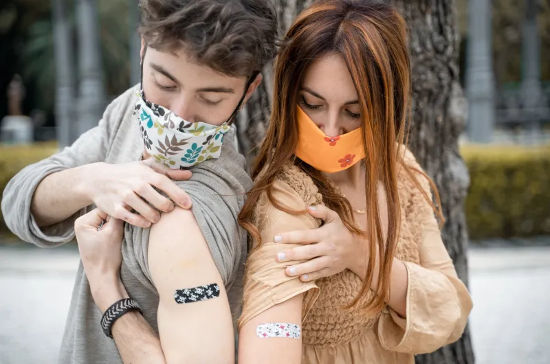 couple of young people showing the bandage on the arm after getting the vaccination from coronavirus new normal concept of people received the vaccine