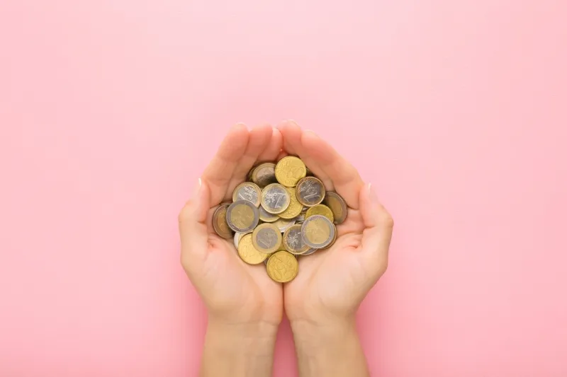 opened young adult woman palms with euro coins on light pink table background pastel color point of view shot closeup top down view