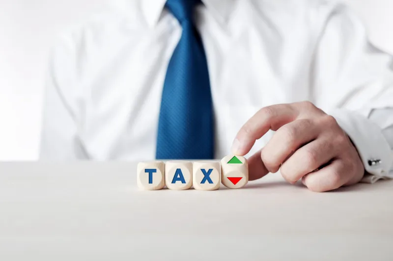 businessman is turning a wooden cube with the arrows symbolizing the tax increase or reduction