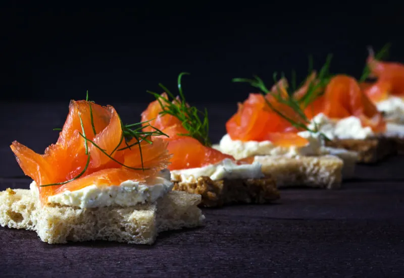 row of festive canapes in star shape with smoked salmon for christmas or new year on a dark wooden background, selected focus, narrow depth of field