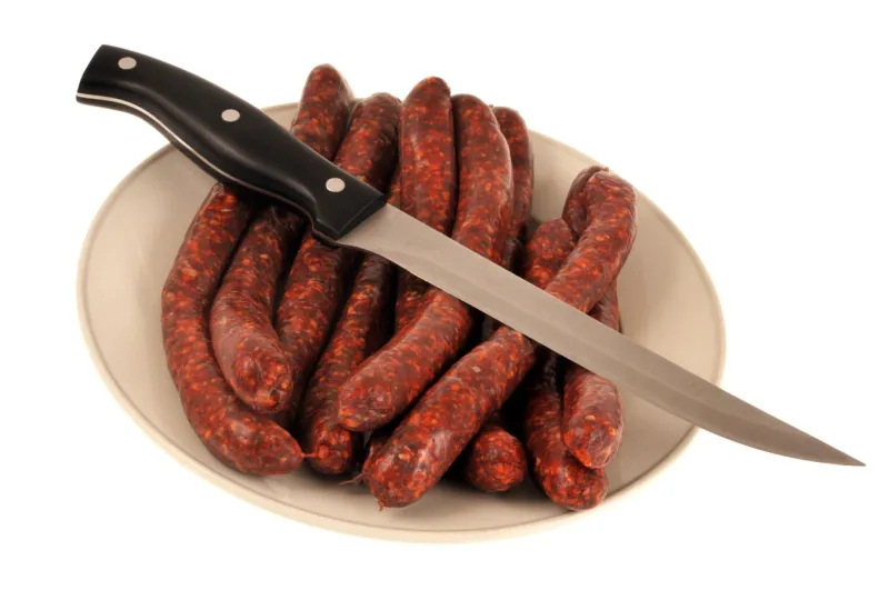 plate of raw merguez on a white background