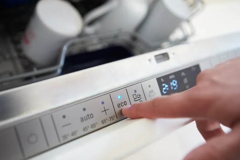 close up of man setting economy cycle on dishwasher