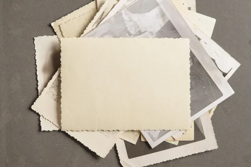 an old faded photo on a stack of old photos on a black page in an old photo album copy space, minimal style, the concept of storing memories