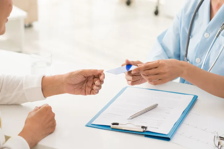 hands of doctor giving health insurance card to senior patient
