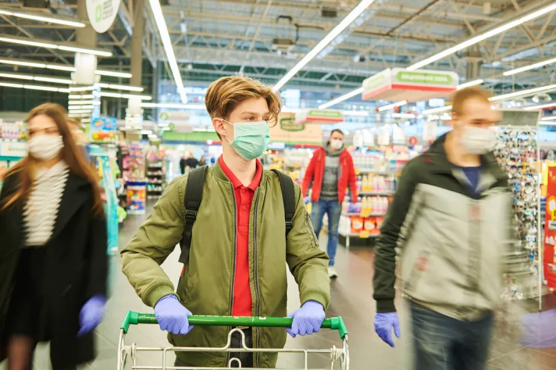 man in mask and protective gloves with shopping cart for food in supermarket shop during quarantine for covid-19 virus outbreak