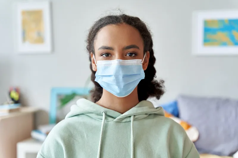 african american teen girl wearing face mask looking at camera at home mixed race teenager during pandemic quarantine concept children safety for covid protection, close up headshot portrait