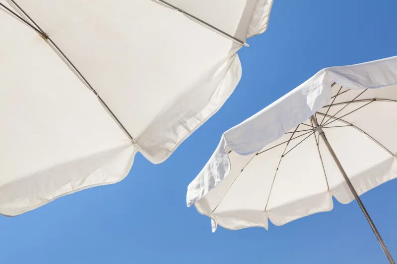 white umbrellas against a blue sky on the french riviera